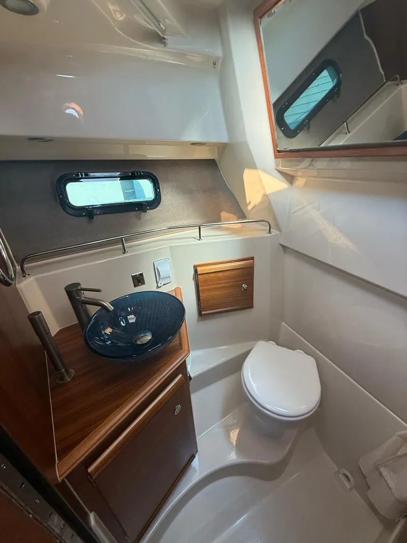 Slide: The Image of 2023 Ranger Tugs R-27 boat bathroom with modern sink, toilet, and wood accents. - 10