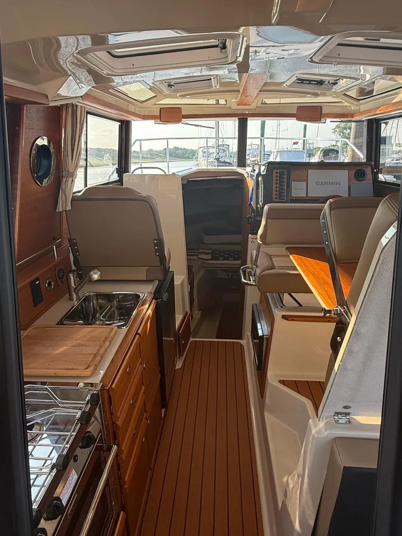 Slide: The Image of 2023 Ranger Tugs R-27 interior with kitchen, seating, and navigation equipment. - 15