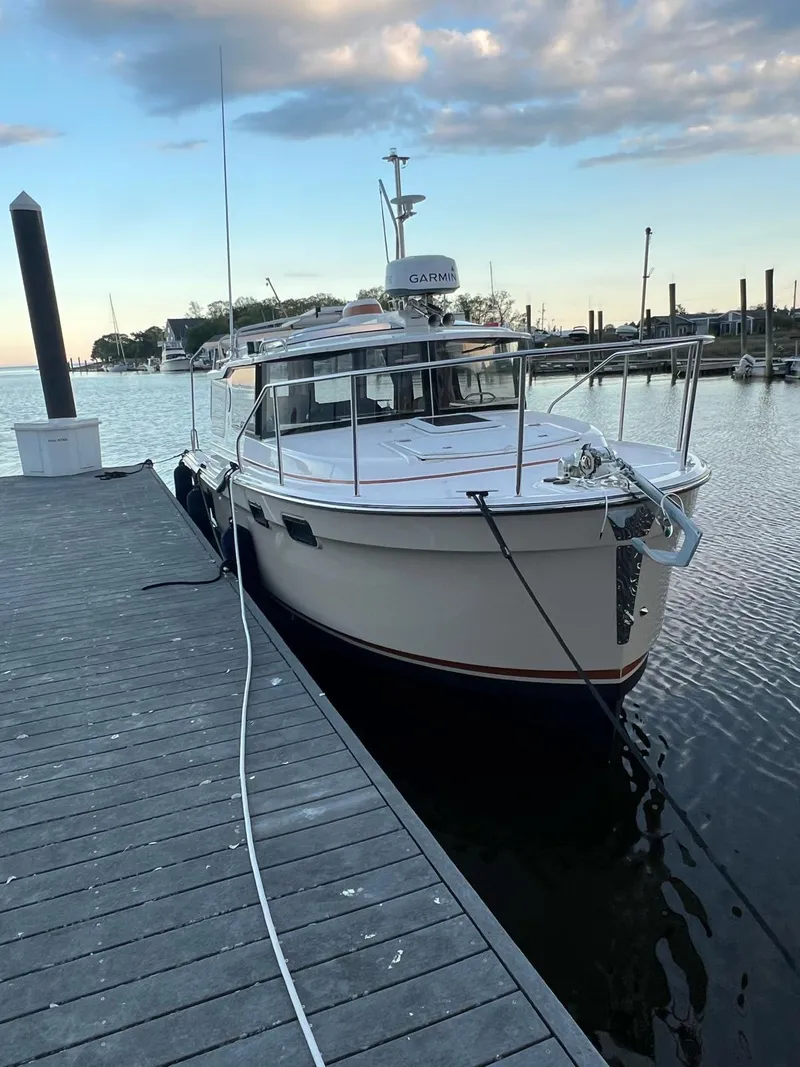 Slide: The Image of 2023 Ranger Tugs R-27 docked at a marina under a cloudy sky. - 23