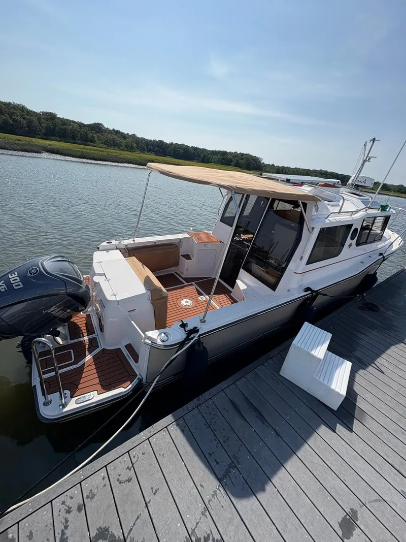Slide: The Image of 2023 Ranger Tugs R-27 boat docked, featuring a canopy and outboard motor. - 4