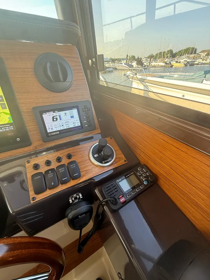Slide: The Image of 2023 Ranger Tugs R-27 helm with navigation controls and marina view. - 8