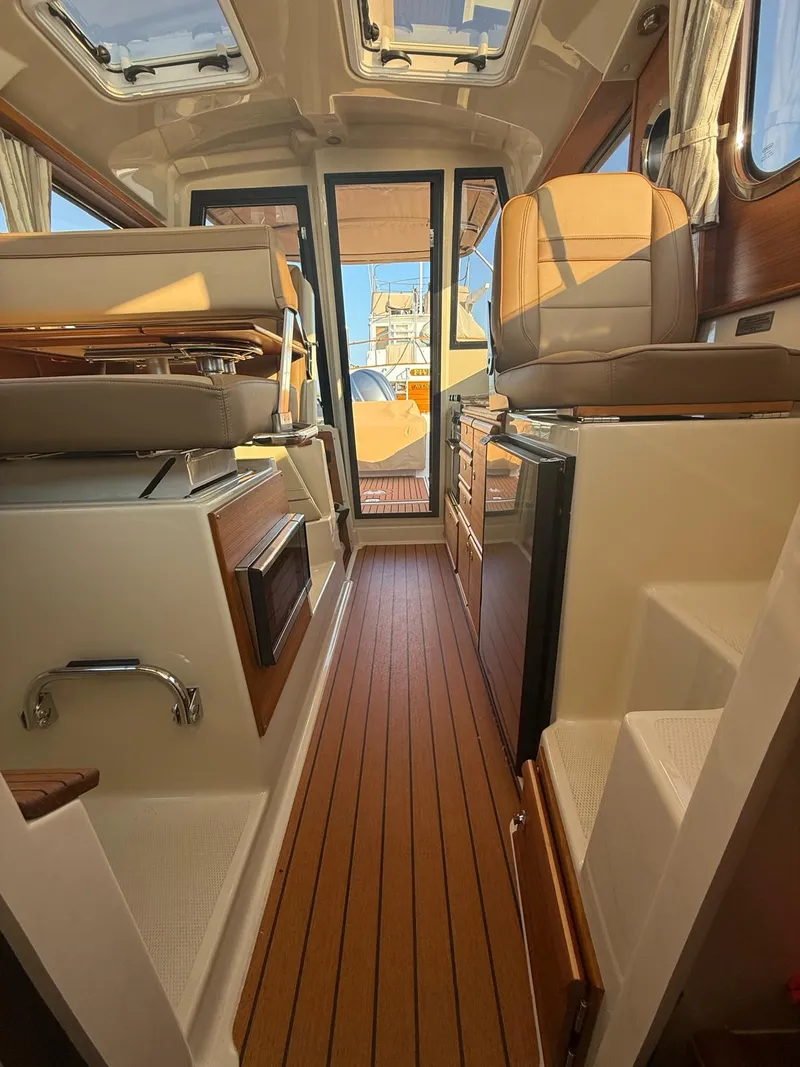 Slide: The Image of Interior of 2023 Ranger Tugs R-27 boat, featuring wood flooring and leather seating. - 9