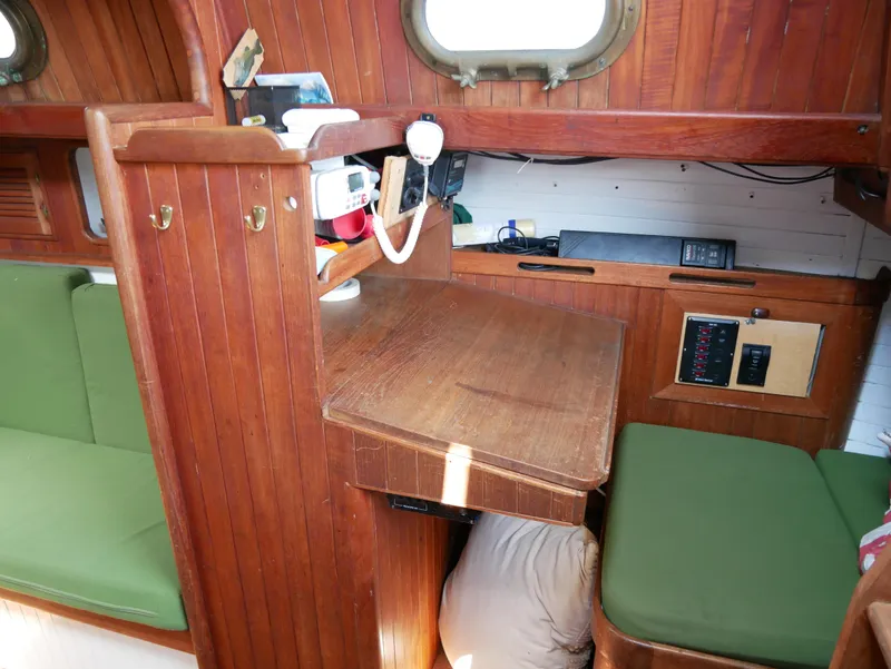 Slide: The Image of 1978 Baba 30 sailboat interior with wooden desk and green cushions. - 12