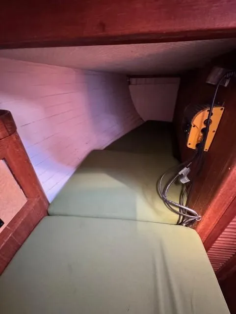 Slide: The Image of 1978 Baba 30 sailboat interior with green cushion and wooden paneling. - 13
