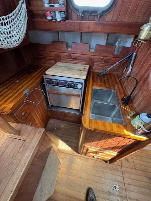 Slide: The Image of 1978 Baba 30 yacht kitchen with wooden cabinetry, stove, and sink. - 14