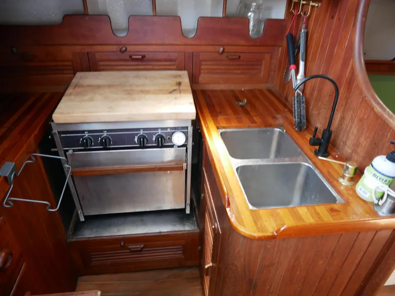 Slide: The Image of Vintage 1978 Baba 30 yacht kitchen with stove, dual sink, and wooden cabinetry. - 15