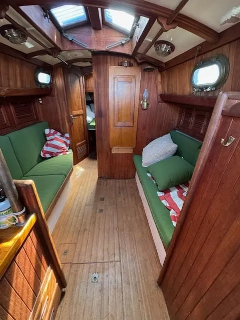 Slide: The Image of Interior of a 1978 Baba 30 sailboat with wooden paneling and green cushions. - 19