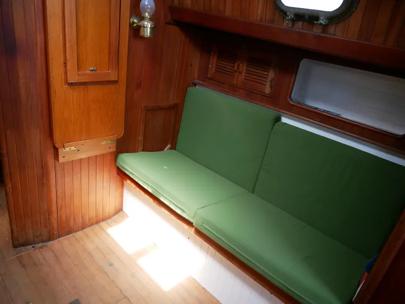 Slide: The Image of Interior of a 1978 Baba 30 sailboat with green cushions and wooden paneling. - 20