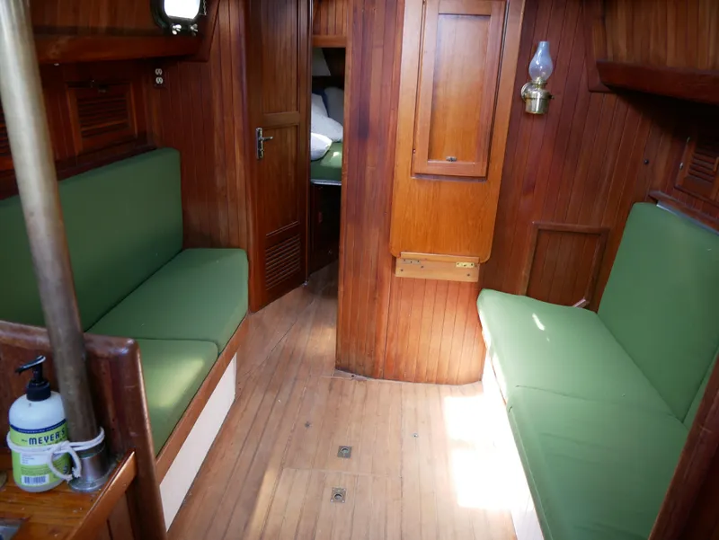 Slide: The Image of Interior of a 1978 Baba 30 sailboat with green cushioned seating and wooden paneling. - 21