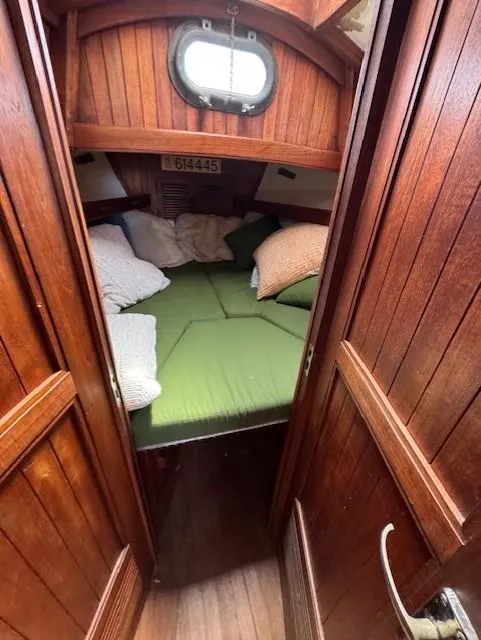 Slide: The Image of Cozy cabin interior of a 1978 Baba 30 sailboat with wooden paneling and green bedding. - 22