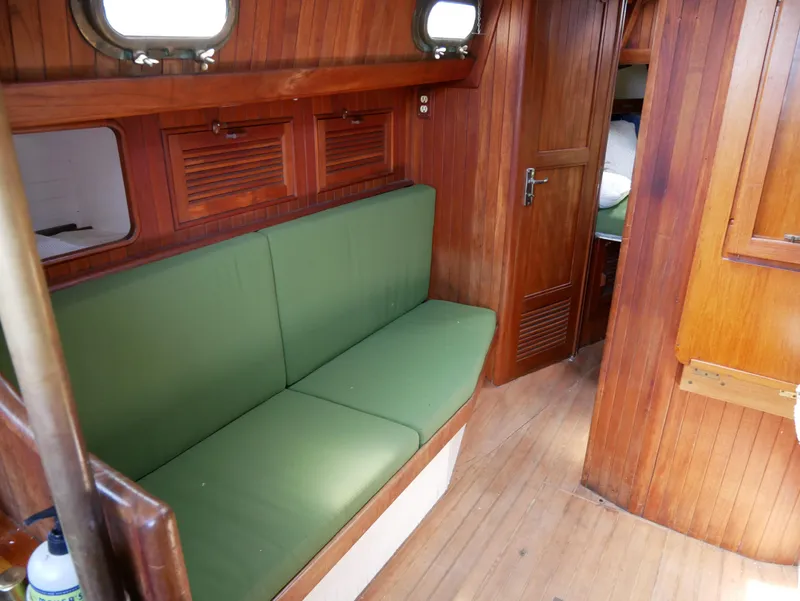 Slide: The Image of Interior of a 1978 Baba 30 sailboat with green cushions and wooden paneling. - 24
