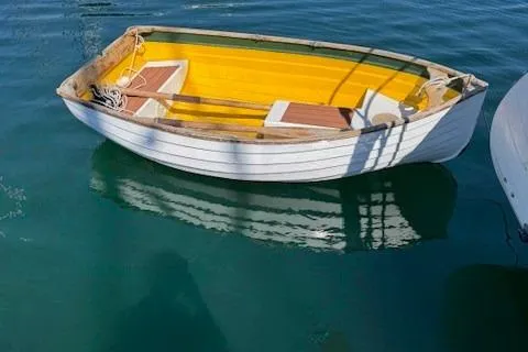 Slide: The Image of Small wooden boat with yellow interior floating on clear blue water. Baba 30, 1978 model. - 30