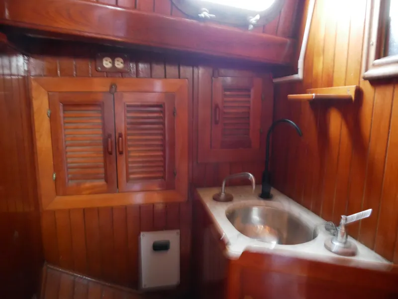 Slide: The Image of Wood-paneled boat interior with sink, cabinets, and porthole, Baba 30, 1978 model. - 32