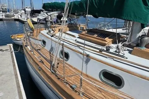 Slide: The Image of 1978 Baba 30 sailboat docked, featuring wooden deck and green canopy. - 5