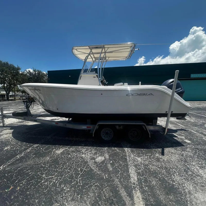 The Image of 2019 Cobia 220 boat on trailer, parked outdoors under clear blue sky. - 0