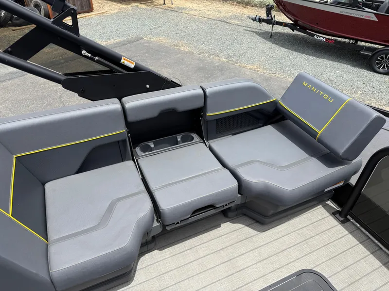 Slide: The Image of 2025 Manitou Explore boat seating with gray upholstery and yellow accents. - 11
