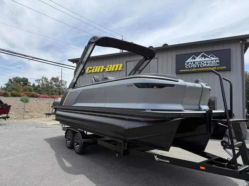 Slide: The Image of 2025 Manitou Explore boat on trailer at California Custom showroom. - 3