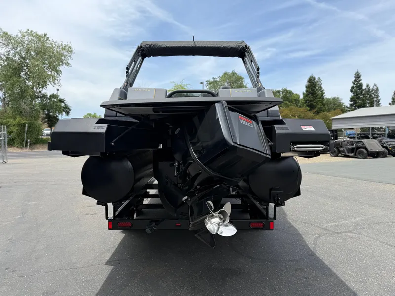 Slide: The Image of Rear view of 2025 Manitou Explore boat with Rotax engine, parked outdoors. - 6