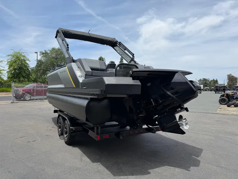Slide: The Image of 2025 Manitou Explore pontoon boat on trailer, parked outdoors under a clear sky. - 7
