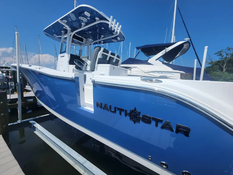 Slide: The Image of 2025 NauticStar 292 Legacy boat docked, featuring sleek blue and white design. - 11