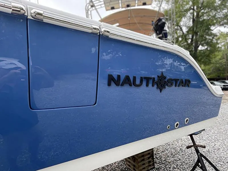 Slide: The Image of 2025 NauticStar 292 Legacy boat, blue hull, docked on gravel. - 4