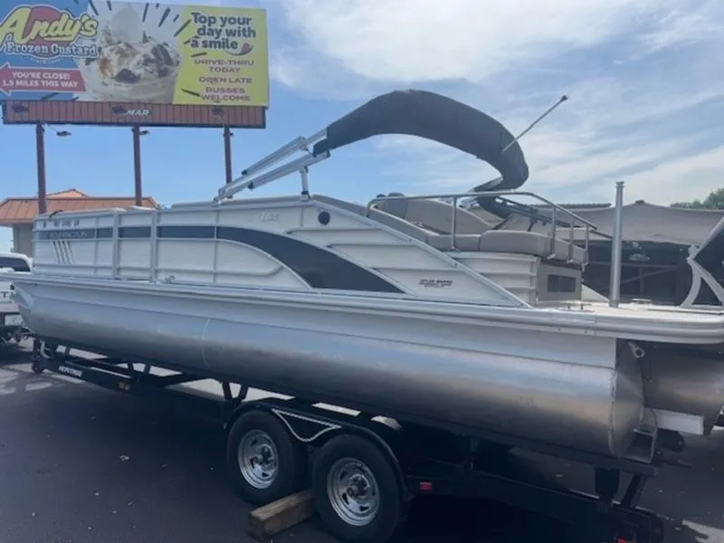 Slide: The Image of 2025 Bennington L Bowrider Swingback 25 LTSB pontoon boat on trailer, parked near Andy's Frozen Custard. - 15