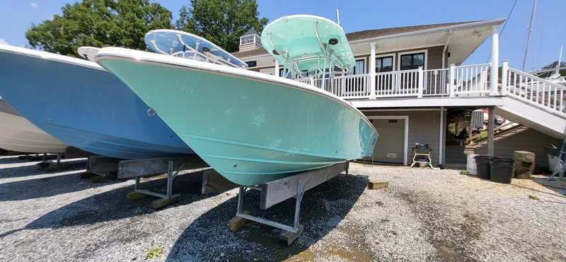 Slide: The Image of 2023 Sea Chaser 23 LX boat in a marina, displayed on stands. - 0