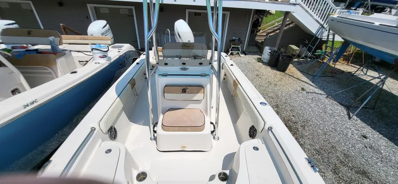 Slide: The Image of 2023 Sea Chaser 23 LX boat interior with seating and console, docked outdoors. - 2