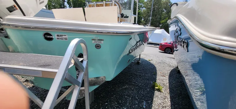 Slide: The Image of 2023 Sea Chaser 23 LX boat in a marina, turquoise hull, parked beside another boat. - 7
