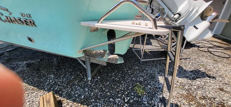 Slide: The Image of 2023 Sea Chaser 23 LX boat with swim ladder and outboard motor on gravel. - 8