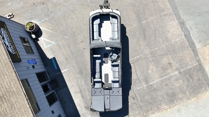 Slide: The Image of Aerial view of 2025 Manitou Explore Dual Engine boat parked on pavement. - 11