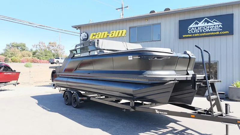 Slide: The Image of 2025 Manitou Explore Dual Engine boat on trailer at California Custom dealership. - 3