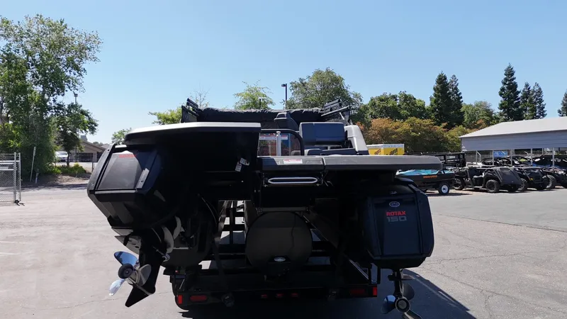 Slide: The Image of 2025 Manitou Explore Dual Engine boat with Rotax 150 engines, parked outdoors. - 8