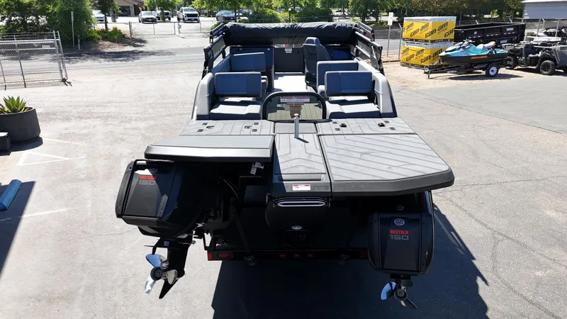 Slide: The Image of 2025 Manitou Explore Dual Engine boat with Rotax engines, parked outdoors. - 9