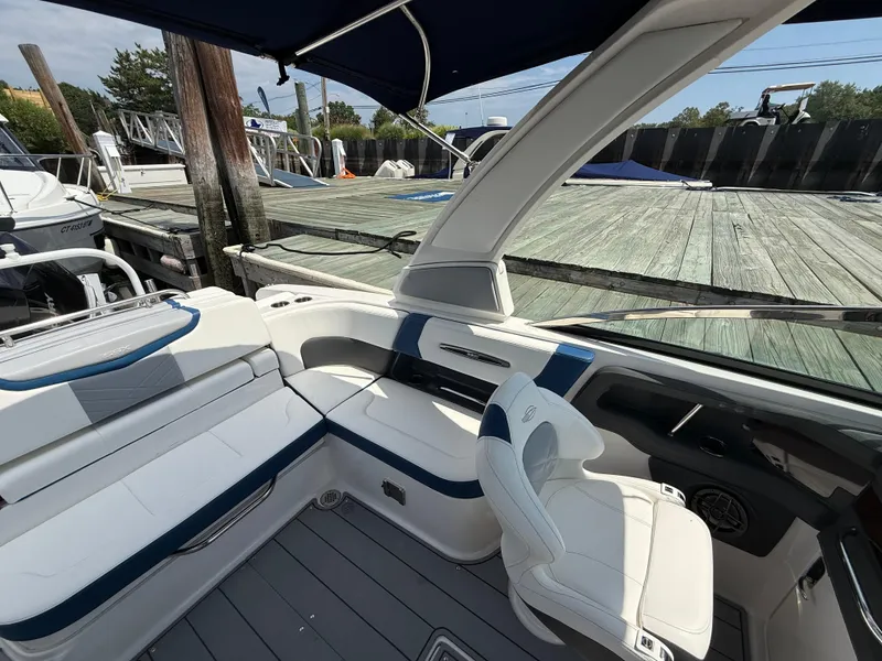 Slide: The Image of 2022 Chaparral 267 SSX OB boat interior with white seating and modern design at dock. - 11