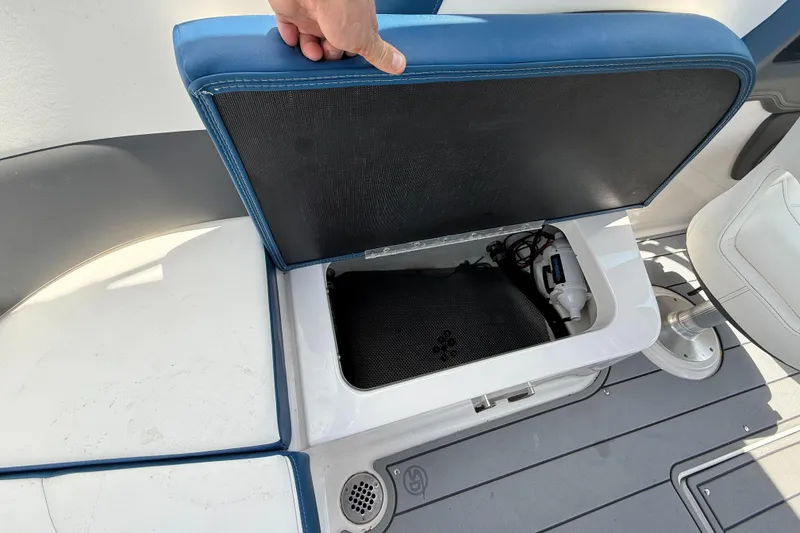 Slide: The Image of 2022 Chaparral 267 SSX OB boat storage compartment with blue cushioned seat. - 14