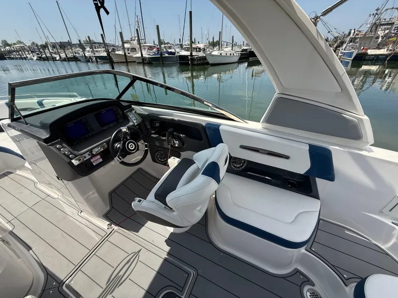 Slide: The Image of 2022 Chaparral 267 SSX OB boat interior with helm and seating, docked at marina. - 15
