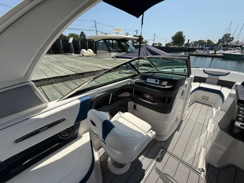 Slide: The Image of 2022 Chaparral 267 SSX OB boat interior with helm and seating at a marina. - 16