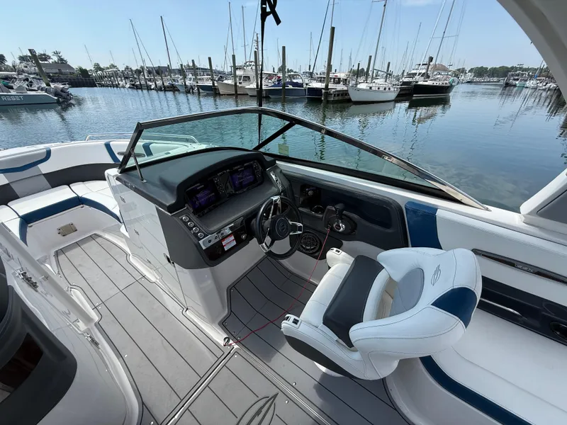 Slide: The Image of 2022 Chaparral 267 SSX OB boat interior with helm, luxurious seating, and marina view. - 19