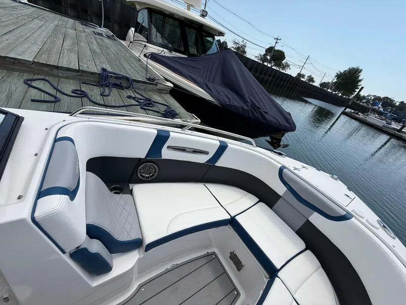 Slide: The Image of 2022 Chaparral 267 SSX OB boat interior with white and blue seating at dock. - 25