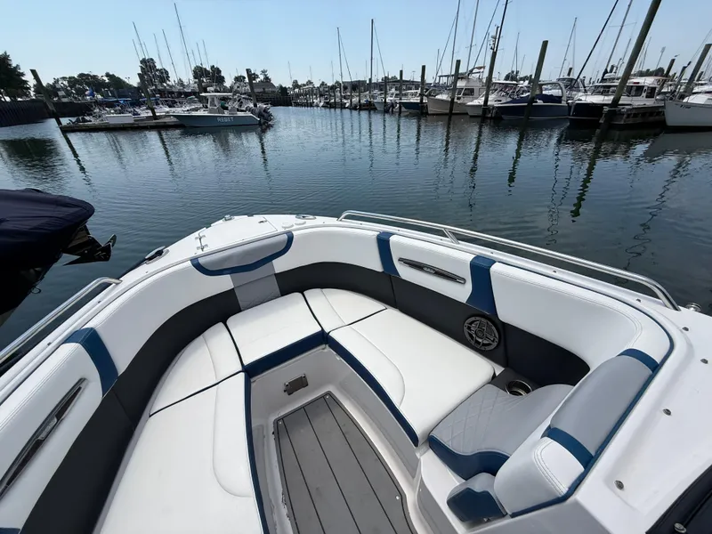 Slide: The Image of 2022 Chaparral 267 SSX OB boat interior with white and blue seating in a marina. - 26