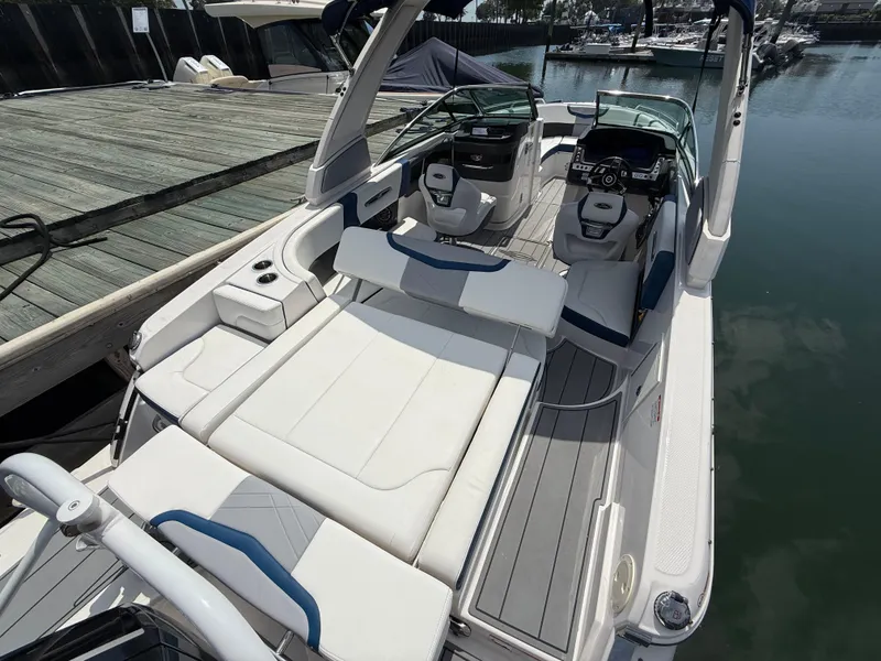 Slide: The Image of 2022 Chaparral 267 SSX OB boat interior with white seating and modern dashboard at a dock. - 7