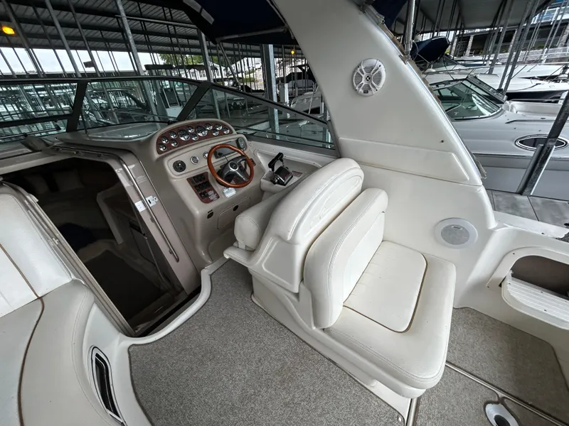Slide: The Image of 2000 Sea Ray 290 Sundancer cockpit with steering wheel and seating in marina. - 2