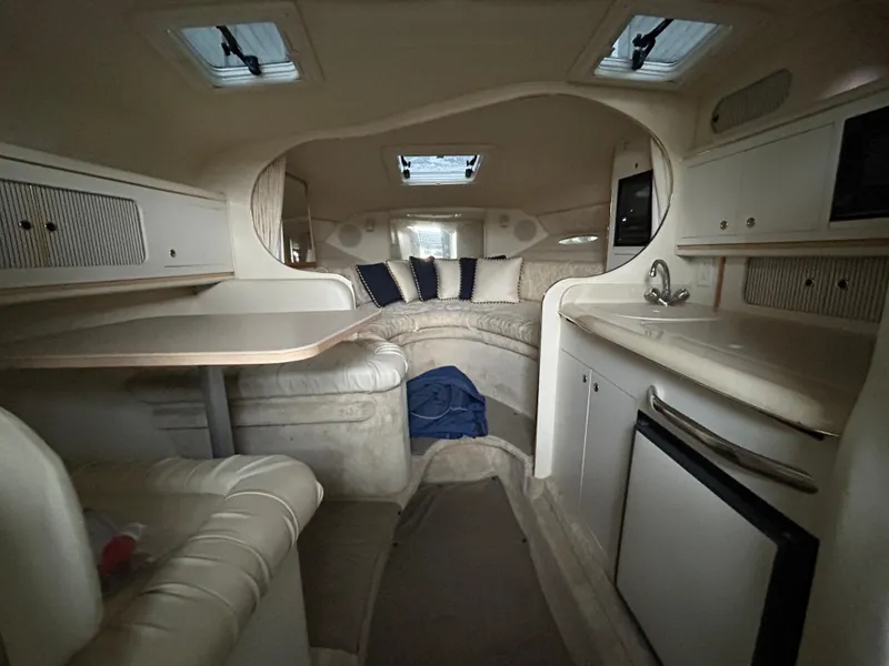 Slide: The Image of Interior of 2000 Sea Ray 290 Sundancer boat, featuring seating, table, and kitchenette. - 8