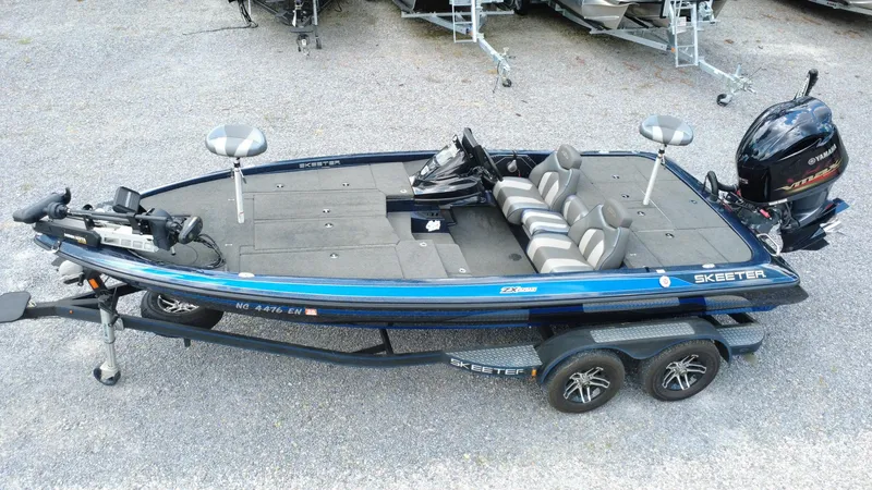 Slide: The Image of 2020 Skeeter ZX225 fishing boat with Yamaha motor on trailer, parked on gravel. - 2
