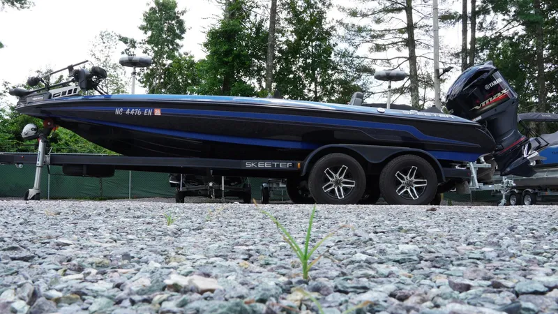 Slide: The Image of 2020 Skeeter ZX225 boat on trailer, parked on gravel, surrounded by trees. - 9