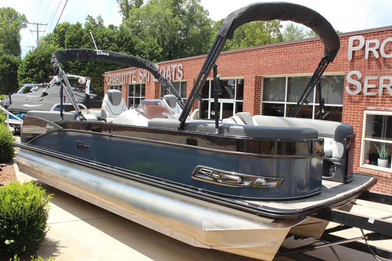 The Image of 2023 Tahoe CASCADE pontoon boat displayed outside a brick building. - 1