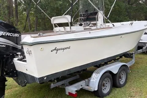 Slide: The Image of 1977 Aquasport 222 boat on trailer, featuring Mercury outboard motor, parked on grass. - 11