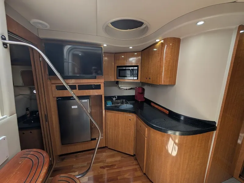 Slide: The Image of 2002 Regal Commodore 3860 yacht interior with kitchenette, wood cabinetry, and modern appliances. - 25
