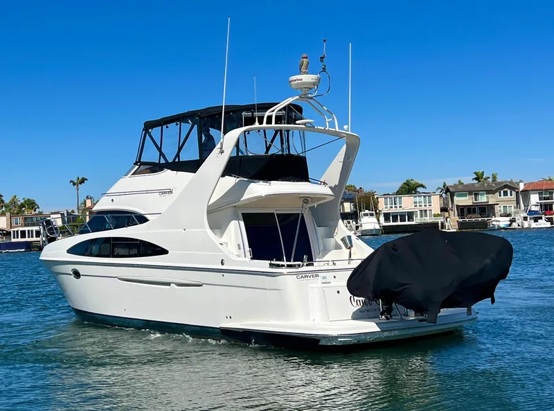 Slide: The Image of 2004 Carver 420 Mariner yacht cruising on a sunny day in a residential marina. - 5